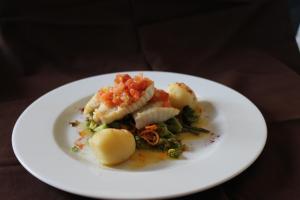 a white plate with a dish of food on a table at Quinta dos Poetas Nature Hotel & Apartments in Olhão
