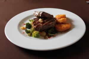 a plate of food with meat and broccoli on a table at Quinta dos Poetas Nature Hotel & Apartments in Olhão