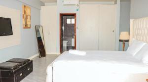 Un dormitorio con una cama blanca y un televisor. en Waterpark view apartment 1A, en Mombasa