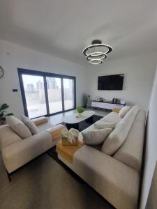 a living room with two couches and a flat screen tv at chic boutique penthouse walk to the beach ashdod in Ashdod