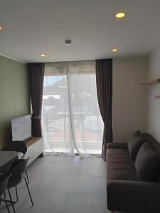 a living room with a couch and a large window at Modern Condo - 1BR T3-528 in Ban Klang