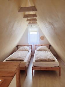 two beds in a attic room with a window at Ferienhaus ROSA mit Sauna in Dorum-Neufeld