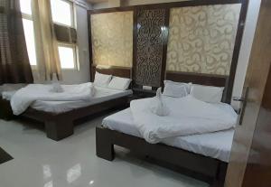two beds in a room with two windows at Hotel Haji Ali - Sahil inn in Ajmer
