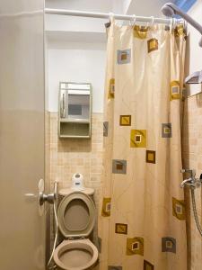 a bathroom with a toilet and a shower curtain at BGC Suites EDSA Makati in Manila +18 photos