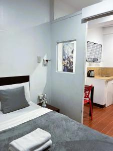 a bedroom with a bed and a red chair at BGC Suites EDSA Makati in Manila