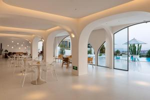 厦门Almeta Designer Hotel的有白色桌椅和窗户的餐厅