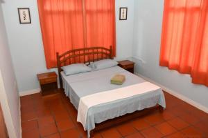 a small bed in a room with orange curtains at Casa Clara - a bright & spacious holiday retreat in Scarborough +20 photos