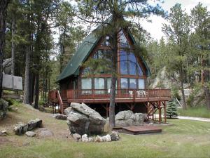 a large wooden cabin with a green roof in the woods at ThunderHeart in Custer