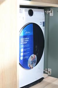 a washing machine with a poster on it at Fjord Stay - Neue Apartment in Kiel - Free Park - 24-7 Check in - "Oslo" in Kiel +2 photos