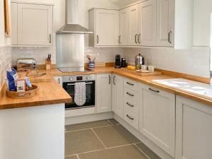 a kitchen with white cabinets and a stove top oven at Barn Cottage in Saint Mawgan