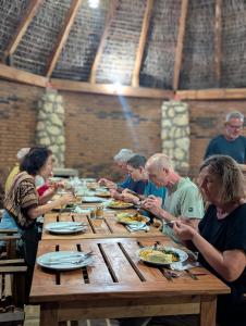 Un grupo de personas sentadas en una mesa comiendo comida en Organica Farmcampus, en Mikindani