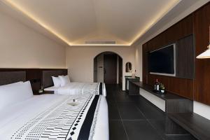 a hotel room with two beds and a flat screen tv at Jinghong City Chenduo Nanshan Hotel in Xishuangbanna International Airport