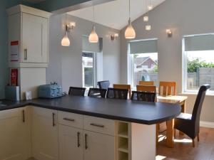 a kitchen with a black counter top and chairs at Grays Cottage in Sewerby