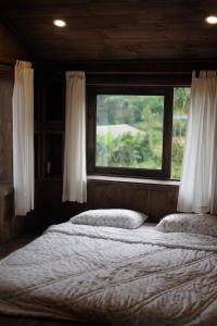 Un dormitorio con dos camas y una ventana. en Olive Cottage Bao Loc, en Tang Jran Dring