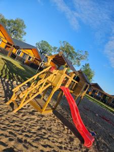a wooden playground with a red slide on the beach at By The Way - domki nad morzem in Paprotno +46 photos