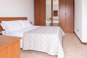 a bedroom with a white bed and a wooden cabinet at IseoLakeRental - Bosco di Lago in Solto Collina
