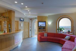 a living room with a red couch and a tv at Hotel La Nuova Montanina in Auronzo di Cadore