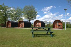 a picnic table in the grass in front of some dome houses at Campingpod in Südbrookmerland