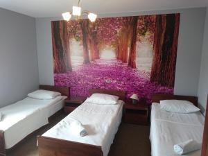 two beds in a room with a painting of a forest at Pokoje Hotelowe Wiktoria in Goczałkowice Dolne
