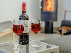 a bottle of wine and two glasses on a table at Finch Cottage in Farnborough