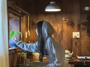 a person in a hoodie holding a plant in a kitchen at Maison De Oliu in Ấp Thiện Lập
