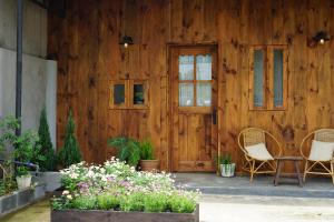 a wooden house with two chairs and a table and flowers at Maison De Oliu in Ấp Thiện Lập