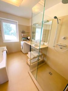 a bathroom with a glass shower and a sink at Ferienwohnung mit Seesicht und Hotelservices in Maria Wörth
