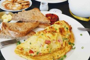 a white plate with an omelet and bread and toast at Pinewood Guest House, Islamabad in Islamabad