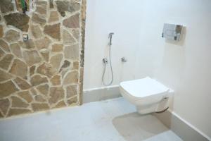 a bathroom with a toilet and a stone wall at Neels Camp Resorts in Panna