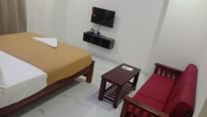 a bedroom with a bed and a chair and a television at Nilton Bay Residency in Kottakupam +60 photos