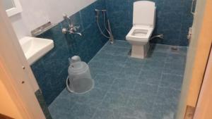 a blue tiled bathroom with a toilet and a sink at Nilton Bay Residency in Kottakupam