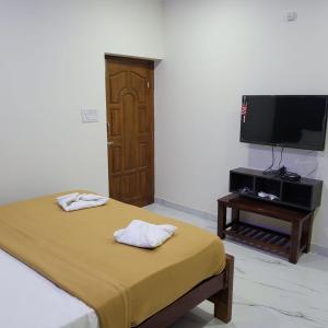 a bedroom with a bed and a flat screen tv at Nilton Bay Residency in Kottakupam