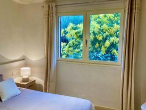 Schlafzimmer mit einem großen Fenster und einem Bett in der Unterkunft Appartement Les marines du soleil in Patrimonio