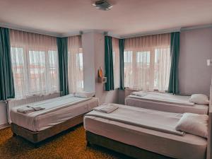 two beds in a room with green curtains and windows at Oreko Express in Afyon