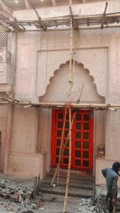 a man standing in front of a red door on a building at Indra Family Homestay - Nearest Area to Triveni Sangam in Prayagraj