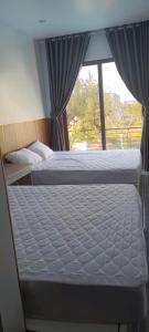 two beds in a bedroom with a window at Hải Nam Homestay Cam Lâm in Cam Lâm