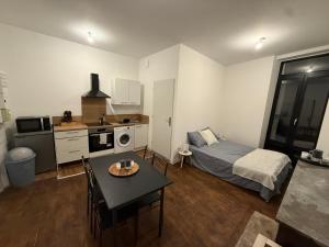 a room with a bed and a table and a kitchen at Appartement rénové, proche gare in Bourg-de-Péage +10 photos