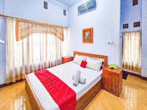 ein Schlafzimmer mit einem Bett mit einer rot-weißen Decke in der Unterkunft RedDoorz Syariah near Stadion Merdeka Jombang in Peterongan + 65 Fotos