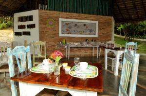 a wooden table with plates and dishes on it at Refúgio do Corsário-Imbassai-Ba in Imbassai