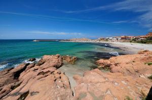 a beach with some rocks and the ocean at Rocce Rosse Isola Rossa in Isola Rossa