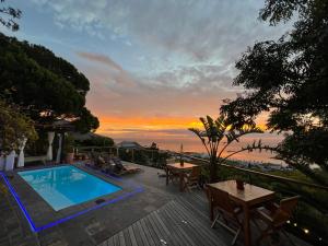 a patio with a swimming pool and a sunset at Boutique@10 in Cape Town