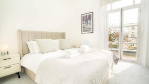 a white bedroom with a large bed and a window at The Cheltenham Suites - Collection of Luxury Flats in Cheltenham