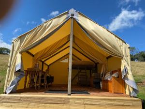 纽波特Usk View Glamping Caerleon的黄色帐篷,配有桌椅