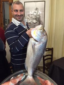 a man holding a fish on top of a table at Hotel Il Pirata in Cinisi