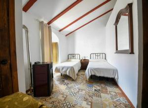 a bedroom with two beds with white sheets and a tile floor at Hospedería de La Corte in Corteconcepción