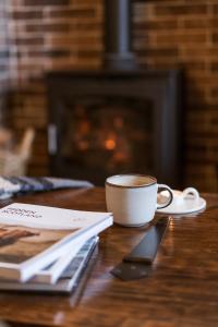 a cup of coffee sitting on a table with a book at Rosebank Cottage - Hot Tub & Log Stove in Alexandria +23 photos