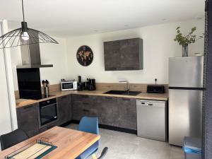a kitchen with a wooden table and a refrigerator at Vacances en Ardèche "maison pont d'arc" in Vallon-Pont-dʼArc