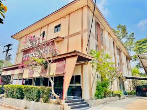 a building with a tree in front of it at พวงชมพูเฮ้าส์ in Sathani Ubon Ratchathani