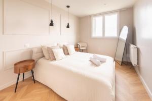 Un dormitorio blanco con una gran cama blanca y una mesa. en Mat&Ness Luxury, en Beauvais