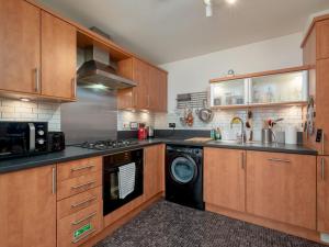 a kitchen with wooden cabinets and a washer and dryer at Modern 2-Bdr Flat in Edinburgh - Pass the Keys in Edinburgh